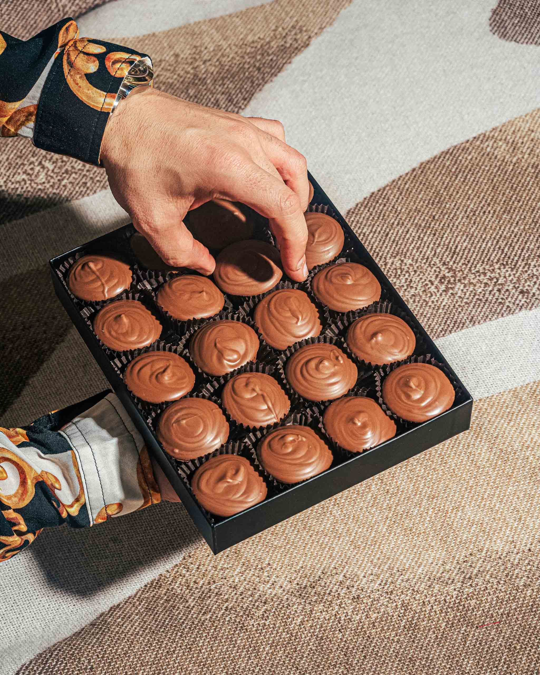 A hand selecting a chocolate from a Compartes gift box